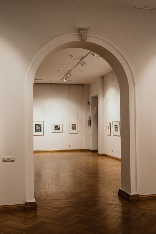 Free Minimalist art gallery interior with elegant arched doorway, showcasing framed artwork. Stock Photo