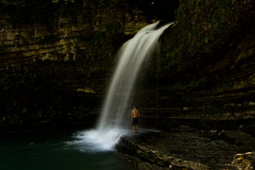 Man Standing near Waterfall