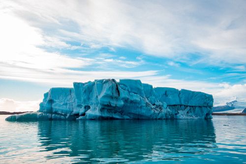 Free Stunning iceberg floating on a serene sea under expansive skies, showcasing nature's beauty. Stock Photo