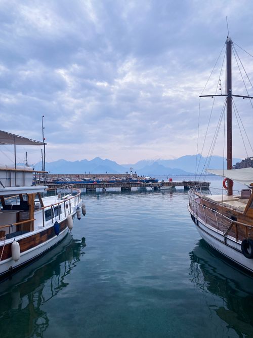 Free A peaceful morning view of moored boats in Antalya marina, with mountains in the background. Stock Photo