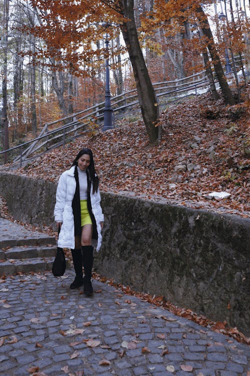 A Woman in White Coat Walking on the Street