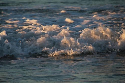 Free Close-up of dynamic ocean waves with foamy splash at sunset, capturing nature's movement. Stock Photo