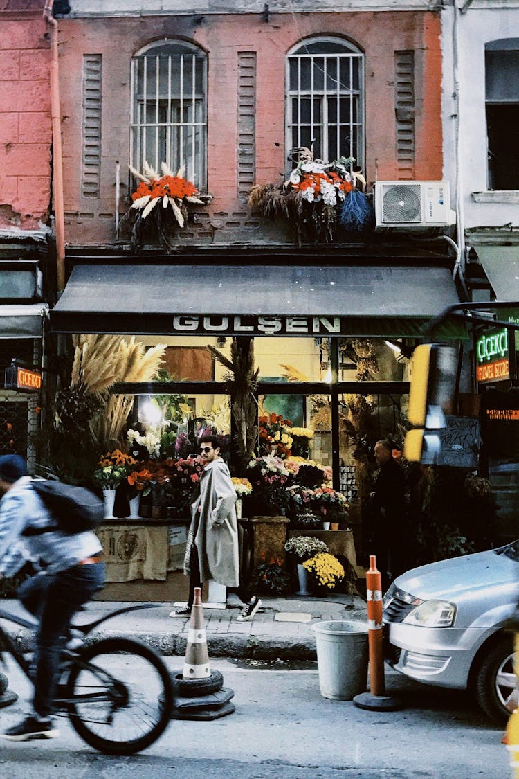 A Man Walking On Sidewalk Beside A Flower Shop