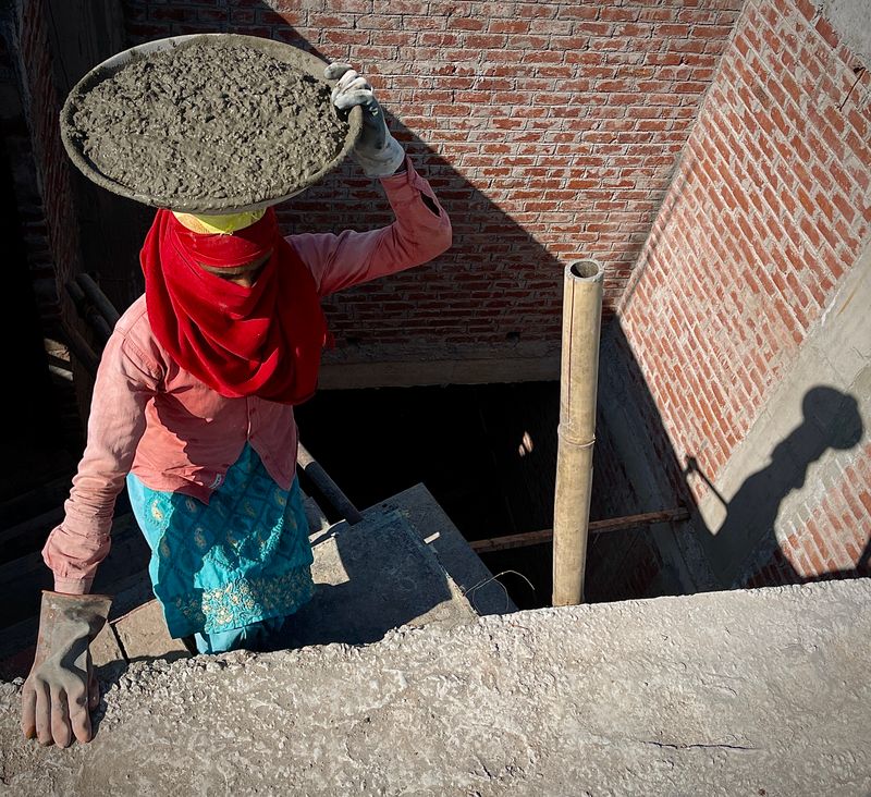 Worker carrying cement at a small building construction site in India