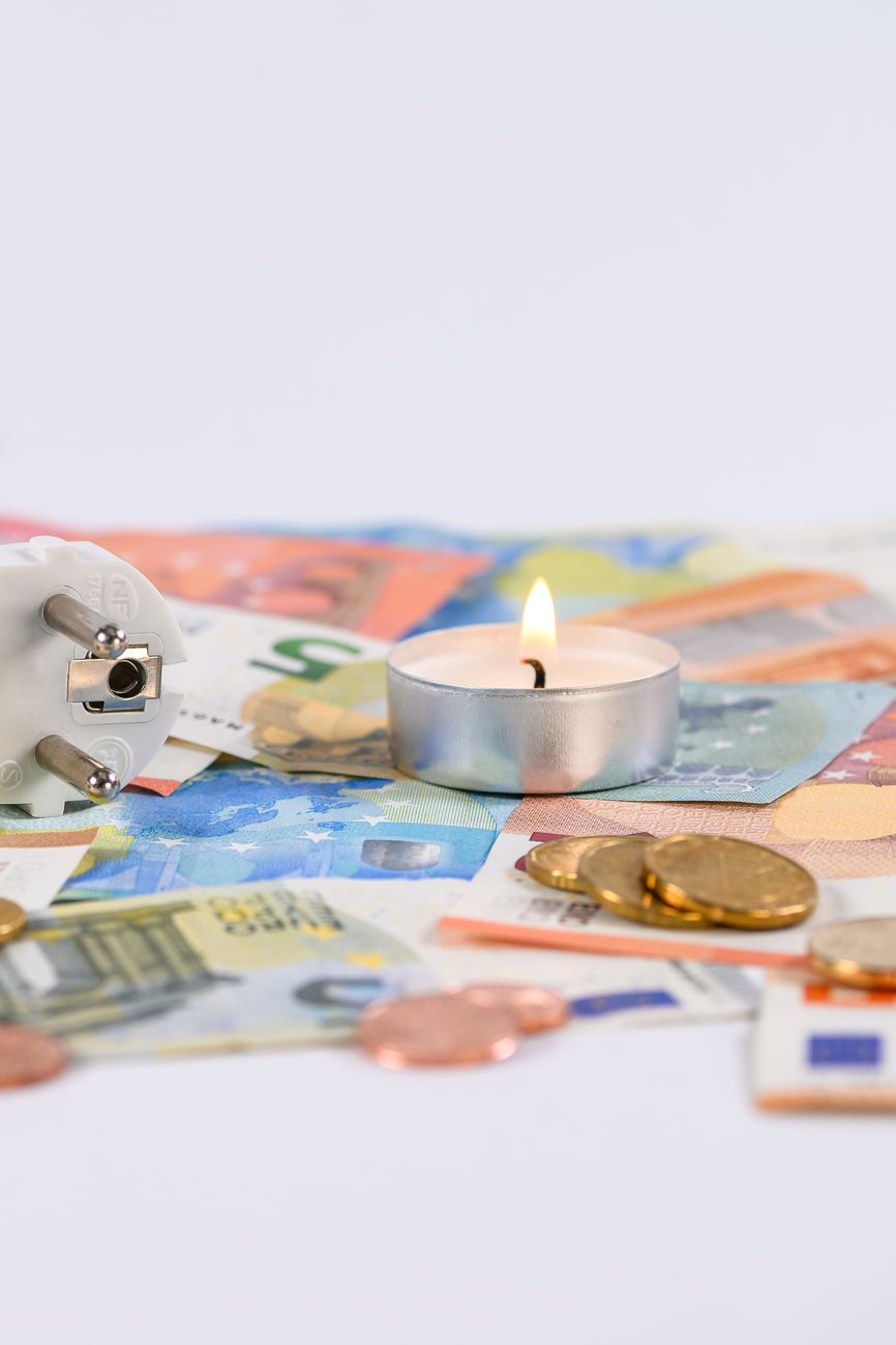 Burning candle on money symbolizing rising costs