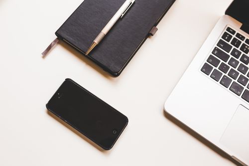 Free A clean workspace setup featuring a laptop, smartphone, and notebook on a desk. Stock Photo