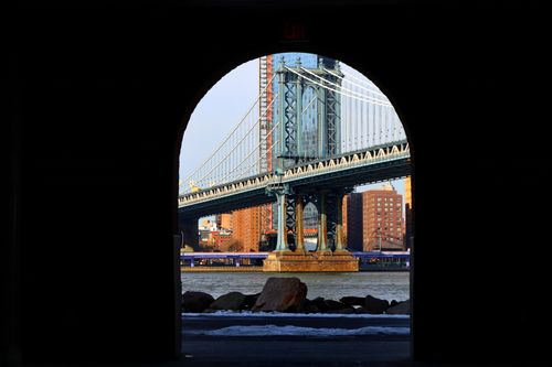 Free Dramatic perspective of the Manhattan Bridge framed by a dark archway, capturing urban architecture in New York City. Stock Photo