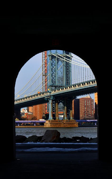 Free View of the Manhattan Bridge framed by an archway, highlighting New York City architecture. Stock Photo