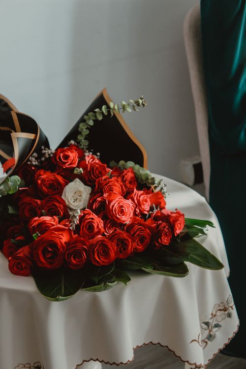 Free Beautiful arrangement of red roses with a single white rose on a decorated table. Stock Photo