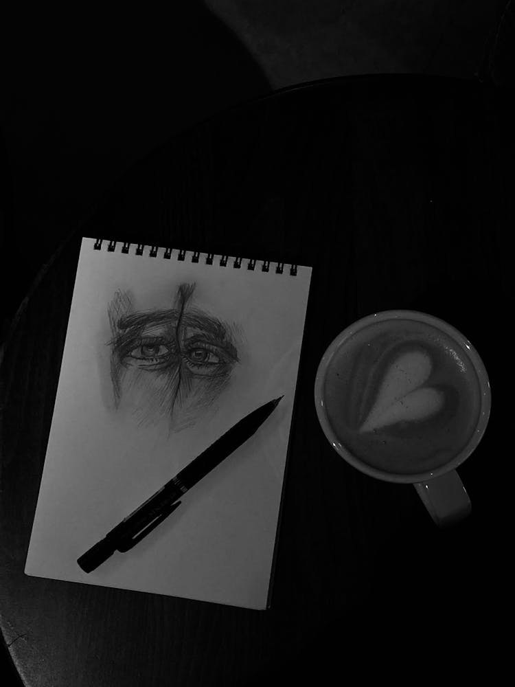 Top View Of A Notepad With A Drawing Beside A Cup Of Coffee