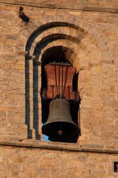 Close-up view of a historic bell tower with intricate brick arch design in warm sunlight.