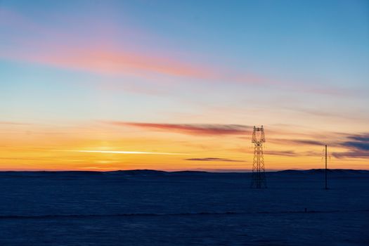 Captivating winter sunset over snowy plains and power lines in Xinjiang, China.