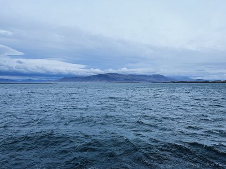 Dramatic Icelandic coastline with rugged mountains and sea under cloudy sky.