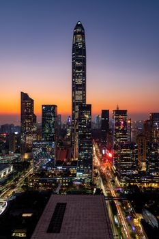 Stunning sunset views of a modern city skyline with illuminated skyscrapers and busy roads.