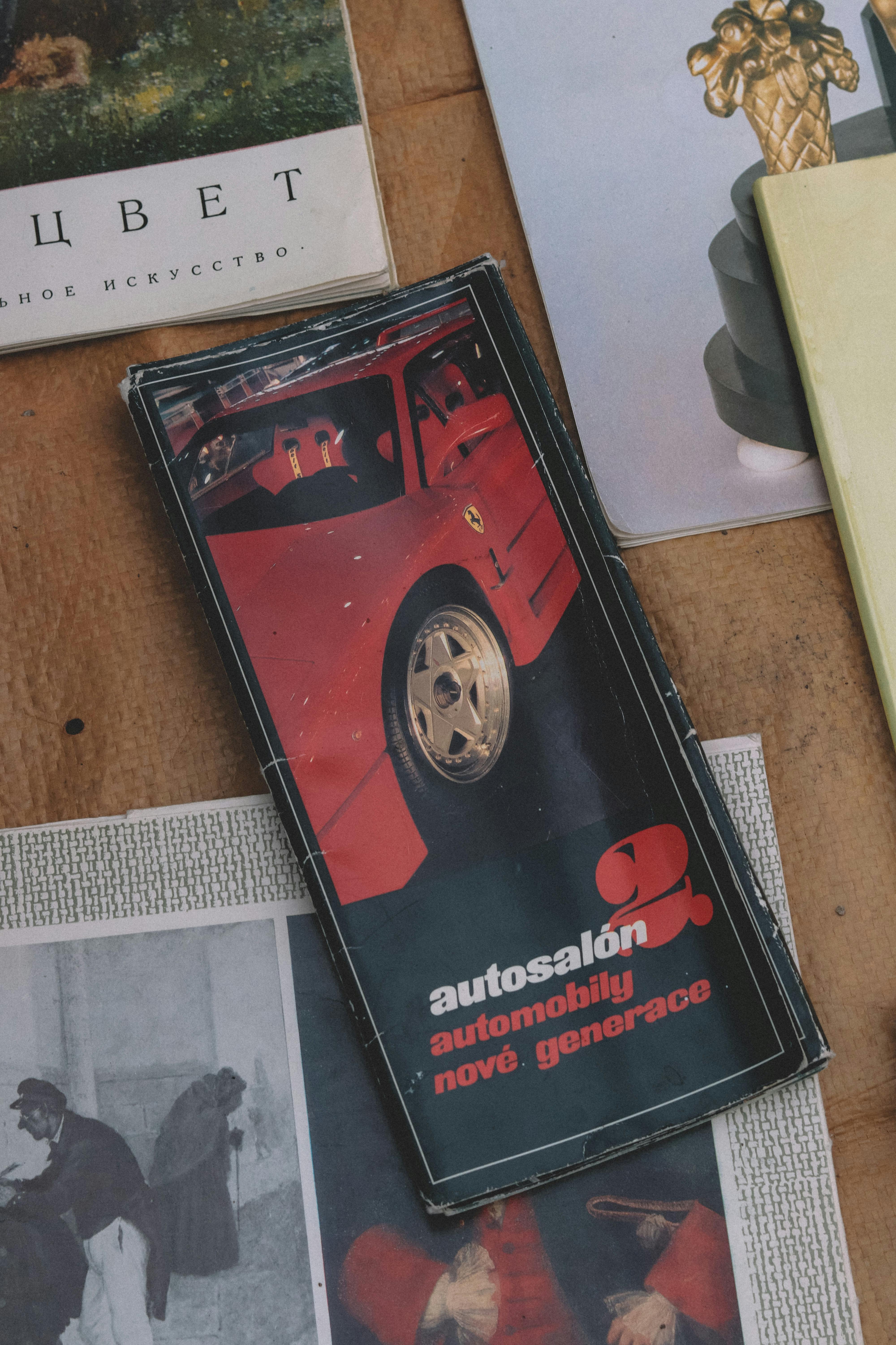 A collage of vintage car brochures and magazines on a wooden surface.