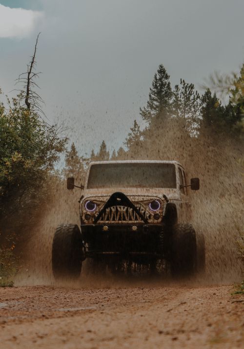Free A Jeep drives through a muddy trail in the forest, showcasing offroading capabilities. Stock Photo