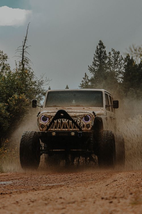 Free Dusty off-road vehicle tackles muddy forest path with dramatic flair. Stock Photo