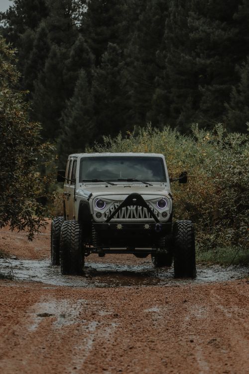 Free A rugged jeep driving through a muddy forest trail, showcasing off-road capability. Stock Photo