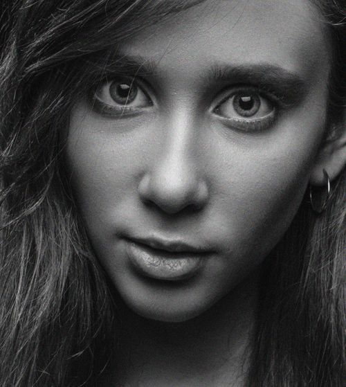 Free Close-up black and white portrait of a woman with hoop earring and intense expression. Stock Photo