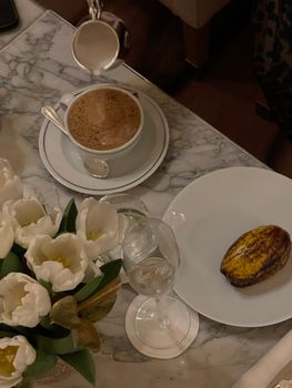Marble table with coffee, tulips, and cocoa pod artfully arranged for a cozy and elegant setting.