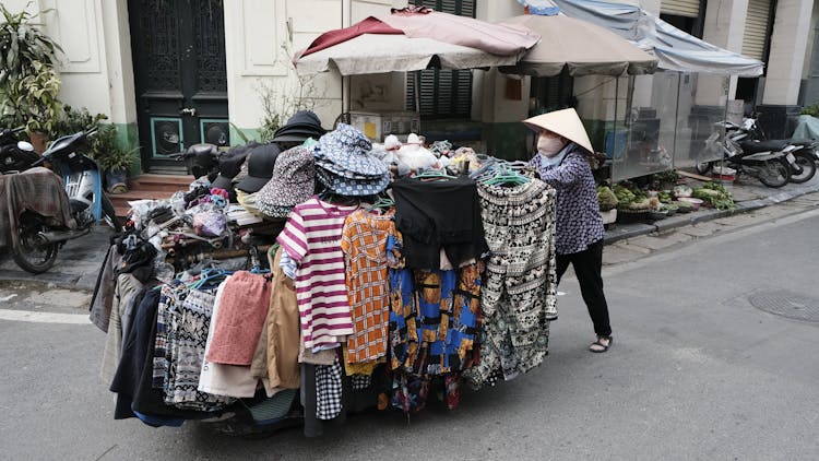 Woman Wearing An Asian Hat Selling Clothing On A Street