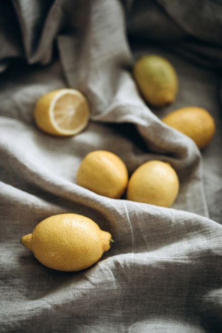A group of fresh lemons displayed on a soft, textured fabric surface. Perfect for kitchen themes.