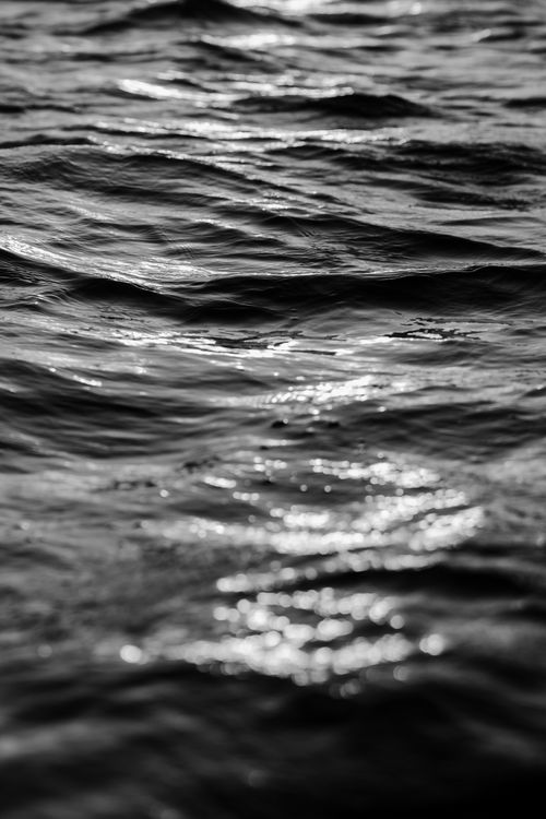 Free Monochrome close-up of ocean waves with sunlight reflections creating a dynamic abstract pattern. Stock Photo
