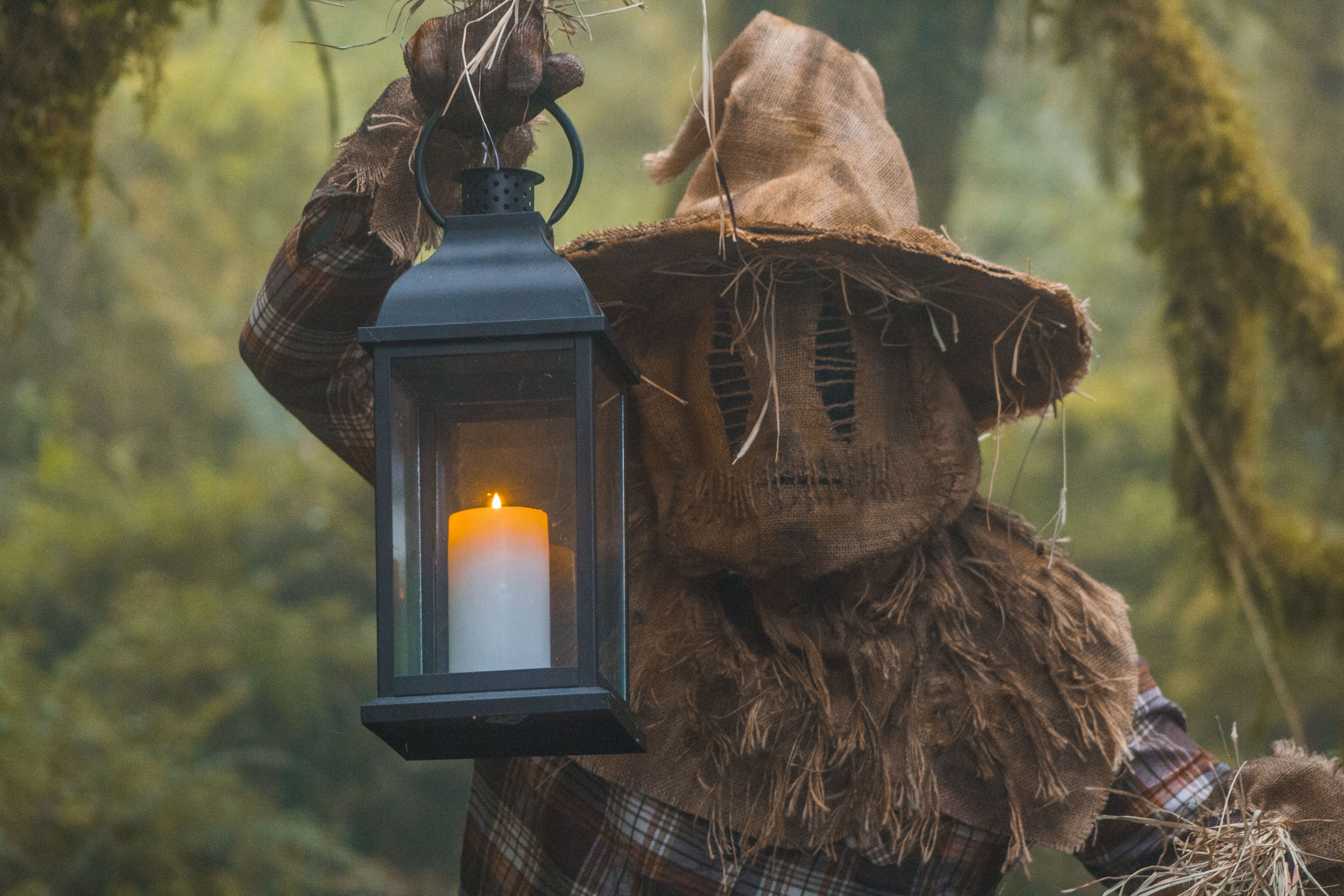 A scarecrow holding a lantern in a misty forest, creating a haunting Halloween atmosphere.