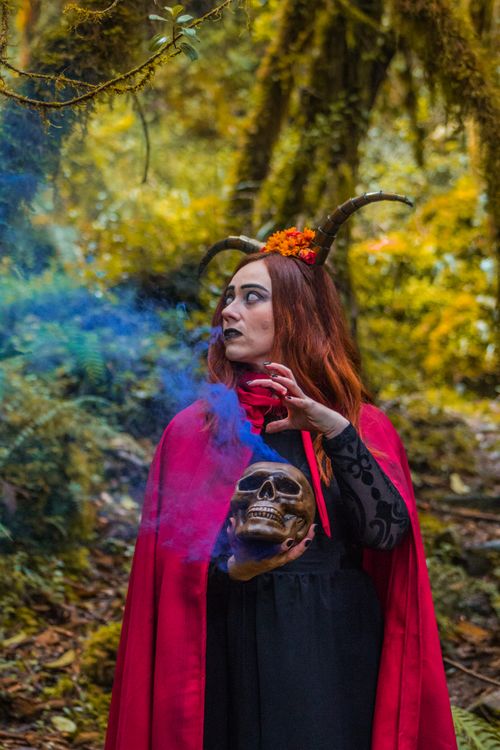 Free A witch holding a skull emits blue smoke in a Colombian forest setting. Stock Photo