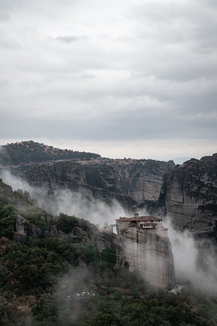 House On Mountain Cliff In Fog