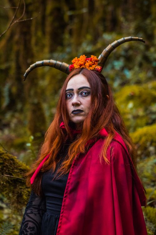 Free Woman in red cape with horns poses in a mystical Colombian forest. Stock Photo
