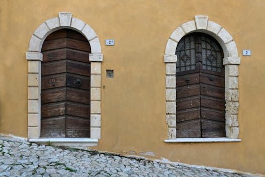 Two antique wooden doors with stone arches in Soave, Italy, showcasing historic architecture.