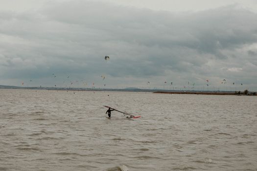 Person with Sailboard on Sea under Clouds