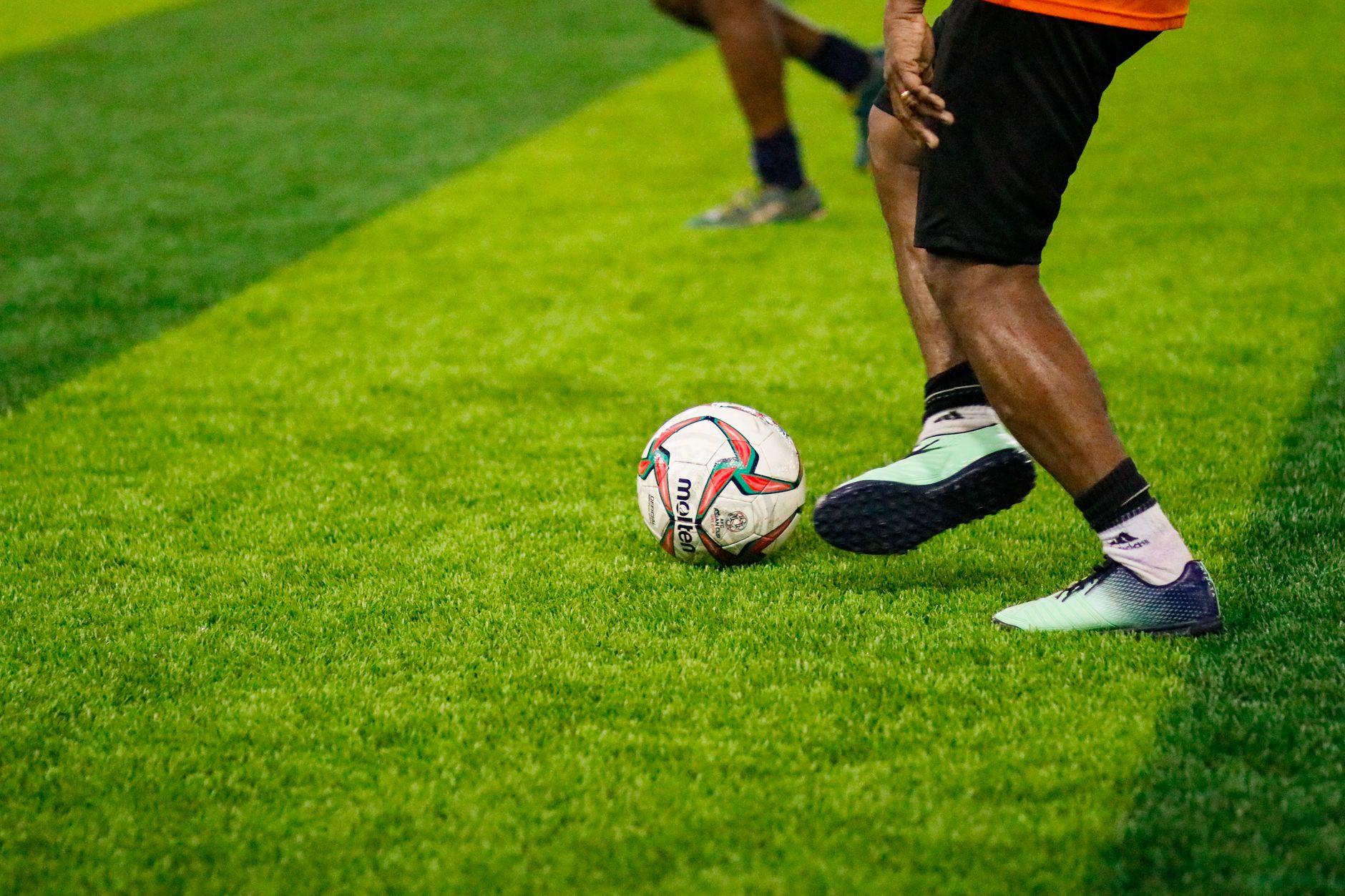 Close-up of footballers in action on a vibrant green field, showcasing athletic motion and competiti
