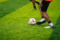 Closeup of a Footballer Kicking a Ball on a Green Lawn