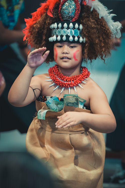 Free Child in traditional costume performing a cultural dance, adorned with feathers and necklaces. Stock Photo