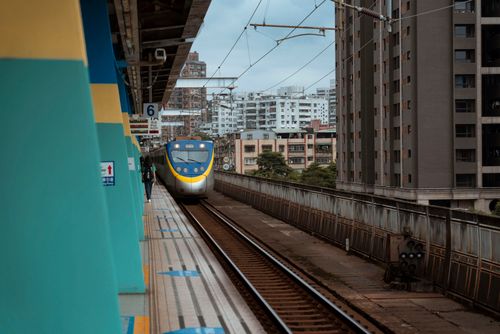 Free A train approaches an urban station platform with buildings in the background, showcasing transportation. Stock Photo