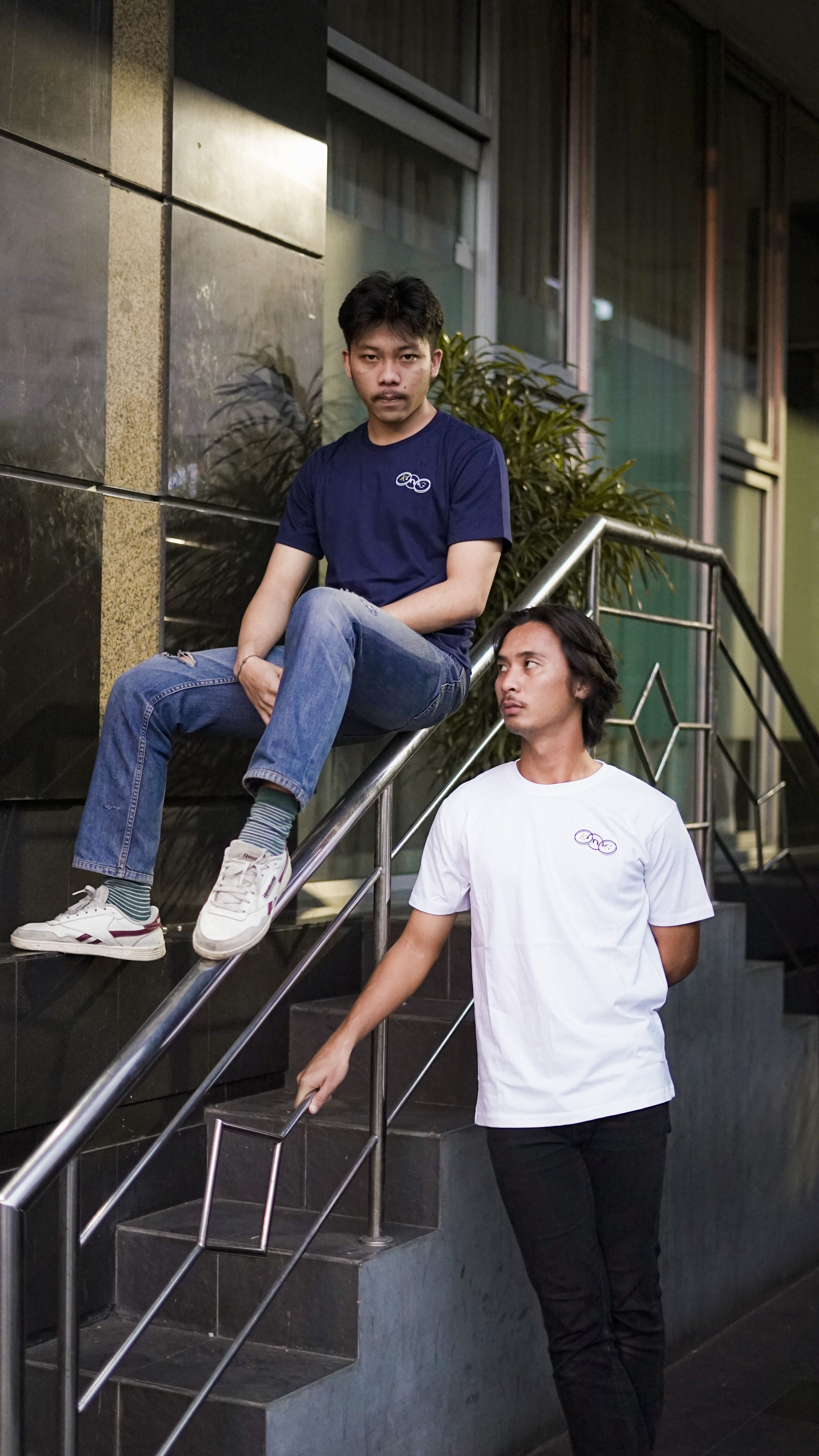Two young adults in casual attire on a staircase in an urban setting.