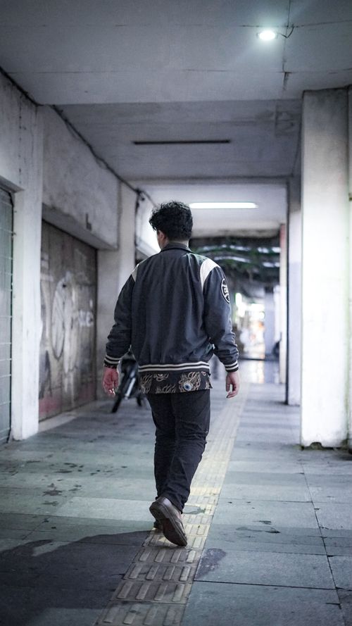 Free Back view of a man walking through an urban subway corridor with dim lighting. Stock Photo