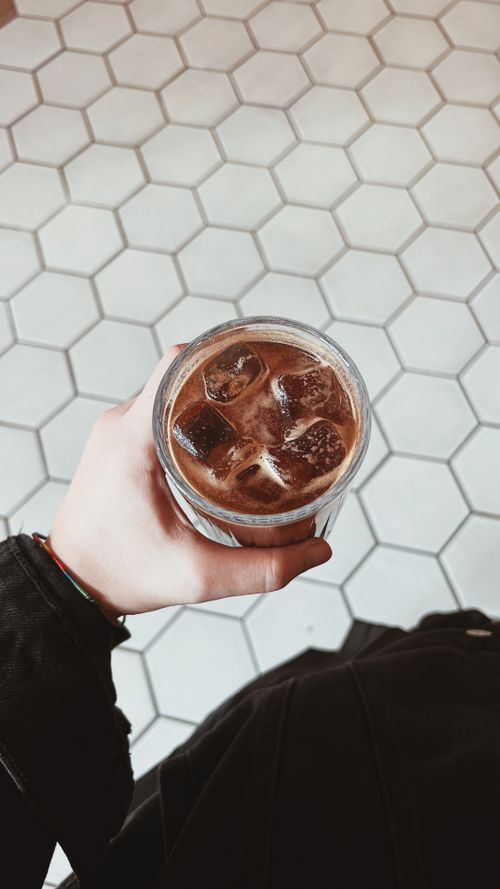 Free Close-up of a person holding a glass of iced coffee, taken from a top view perspective. Stock Photo
