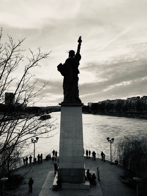 Free Striking monochrome silhouette of the Statue of Liberty in Paris, France against the Seine River. Stock Photo