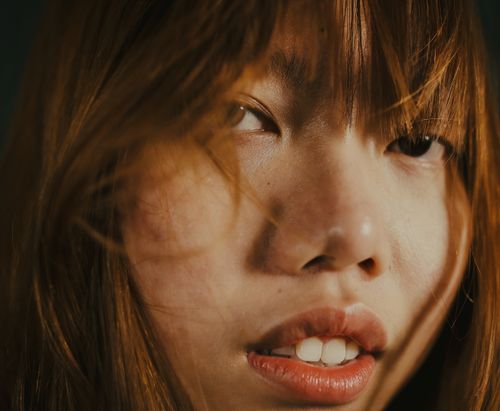 Free Detailed close-up of a young East Asian woman with brown hair and natural makeup. Stock Photo