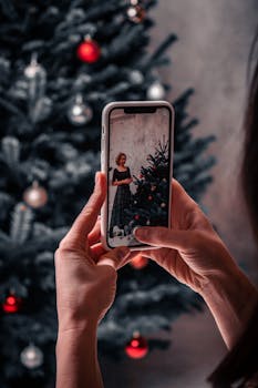A woman captures a holiday moment by photographing a Christmas tree on her smartphone.