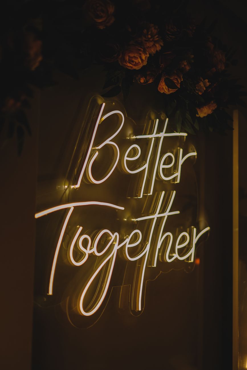 A warmly lit neon sign reading 'Better Together' with floral accents.