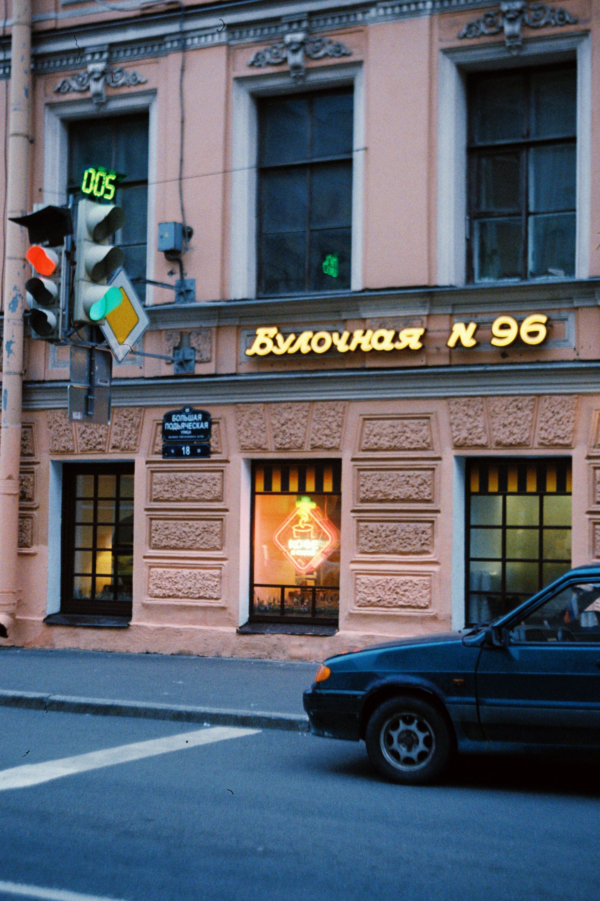 Urban street view of a St. Petersburg bakery with a neon sign and classic architecture.
