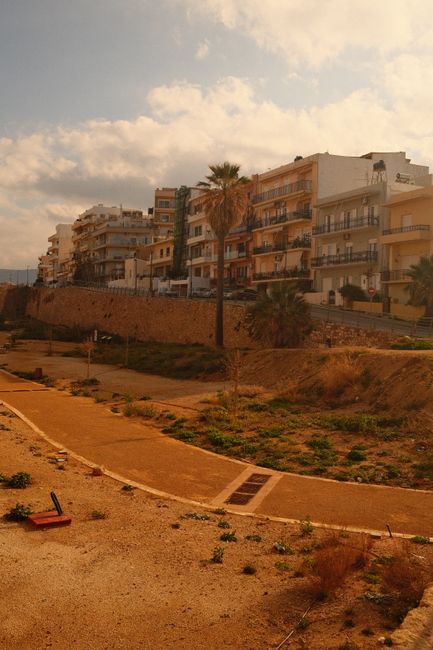 Scenic view of historic coastal buildings with a walkway under a partly cloudy sky.