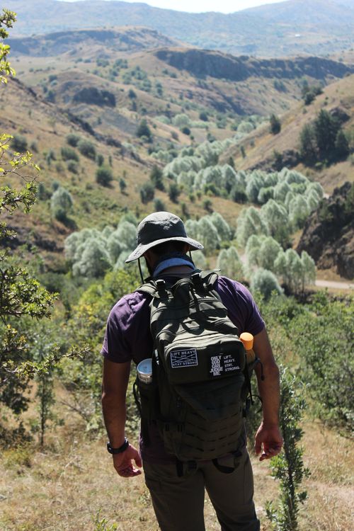 Free Man hiking in mountains with backpack, enjoying scenic outdoor landscape. Stock Photo