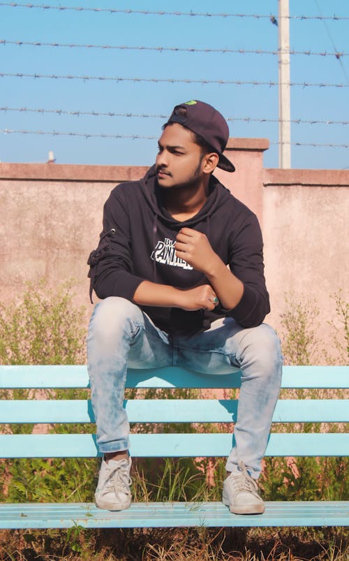 A Guy Sitting On Chair Wearing A Cap