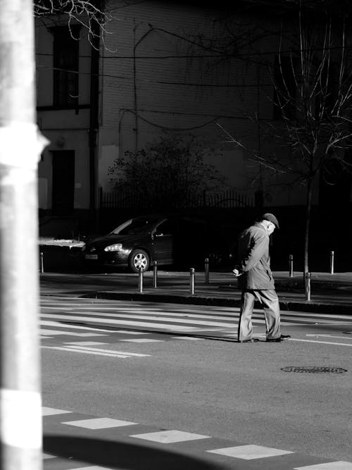 A Grayscale Photo of a Man Walking on the Street