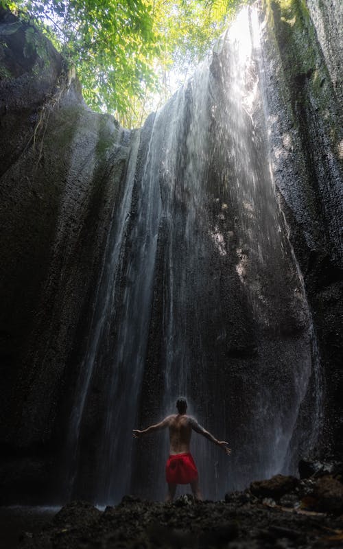 Free Shirtless man Standing under the Waterfalls Stock Photo